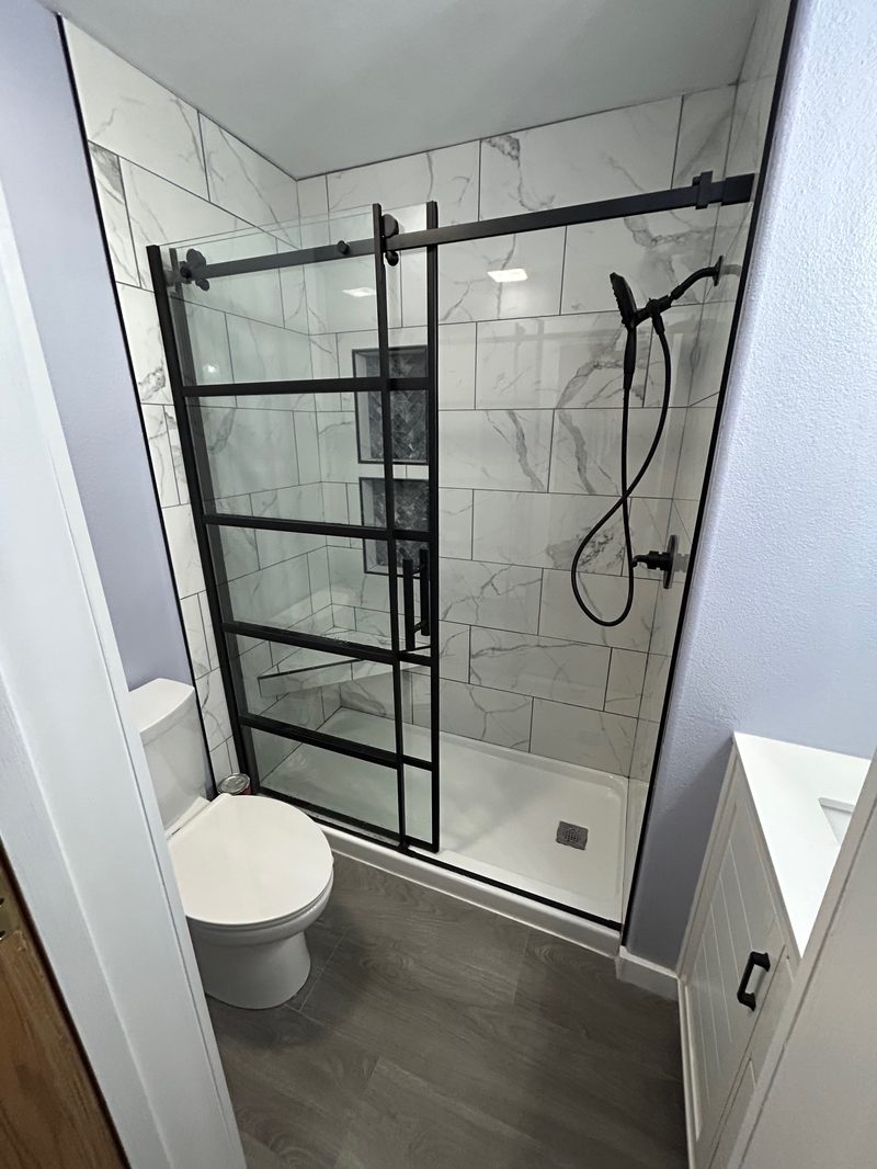 Black-frame glass shower with marble tile